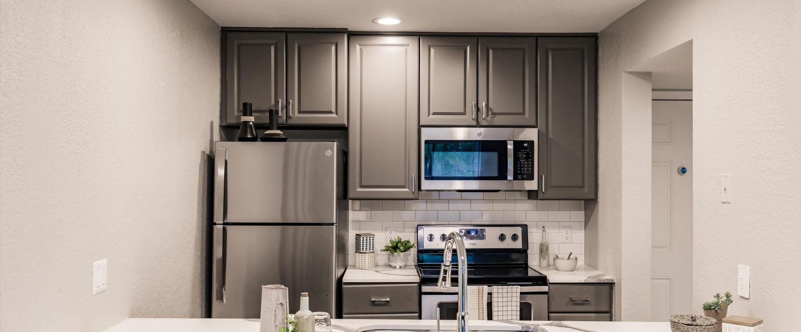 a kitchen with stainless steel appliances and gray cabinets at The Marino