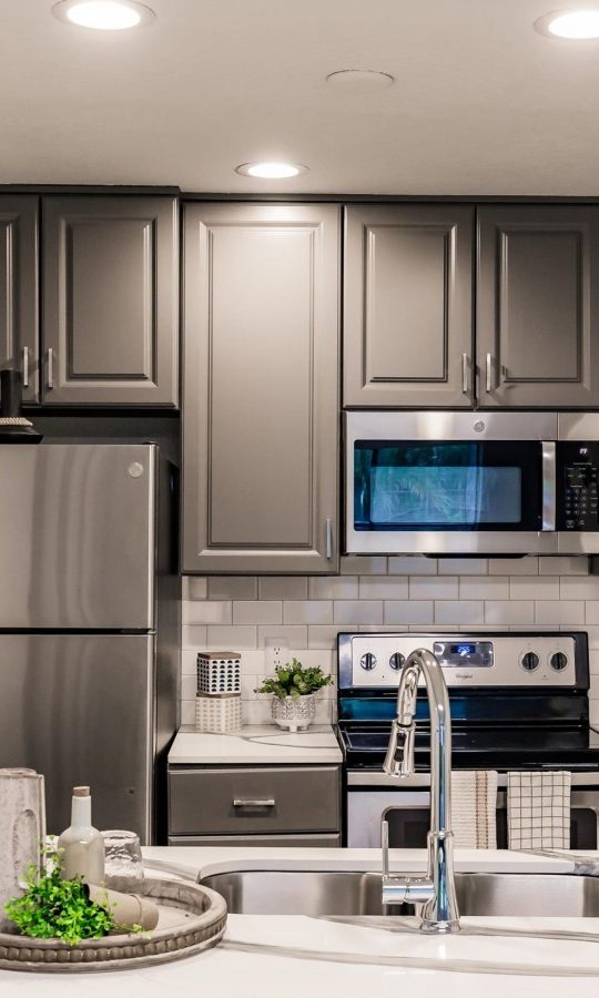 a kitchen with stainless steel appliances and gray cabinets at The Marino