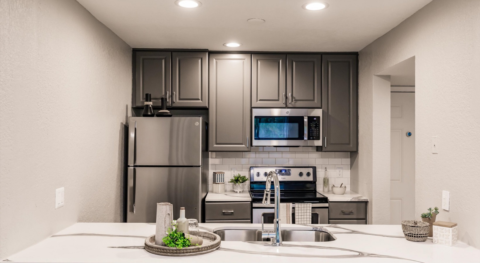 a kitchen with stainless steel appliances and gray cabinets at The Marino