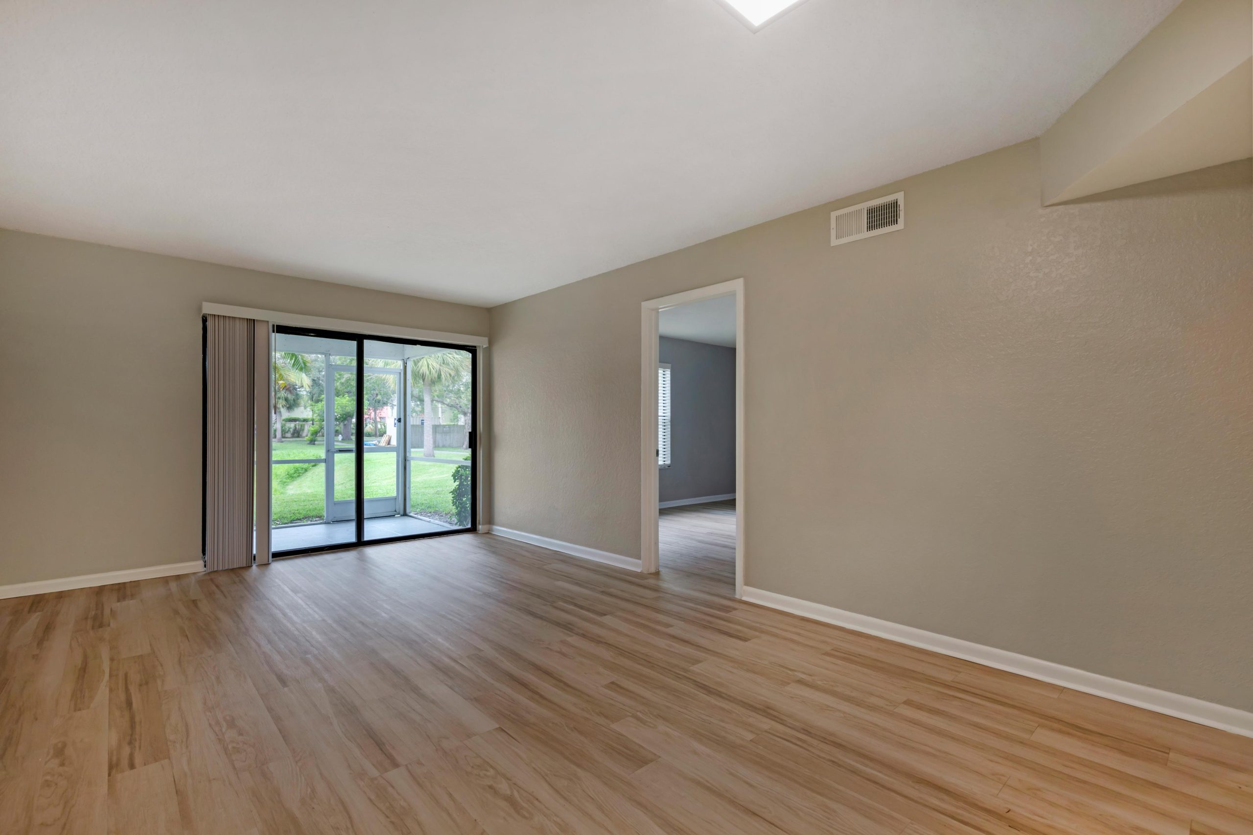 empty living room with sliding glass doors and hardwood floors at The Marino