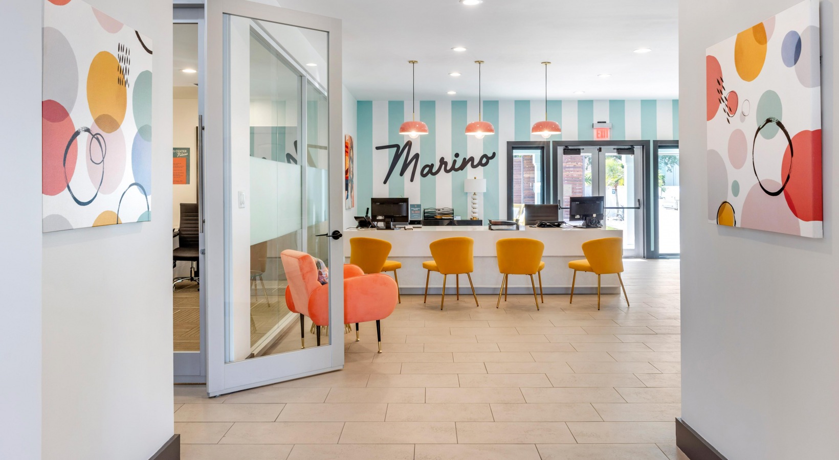 the lobby of a hotel with orange chairs and a large sign at The Marino