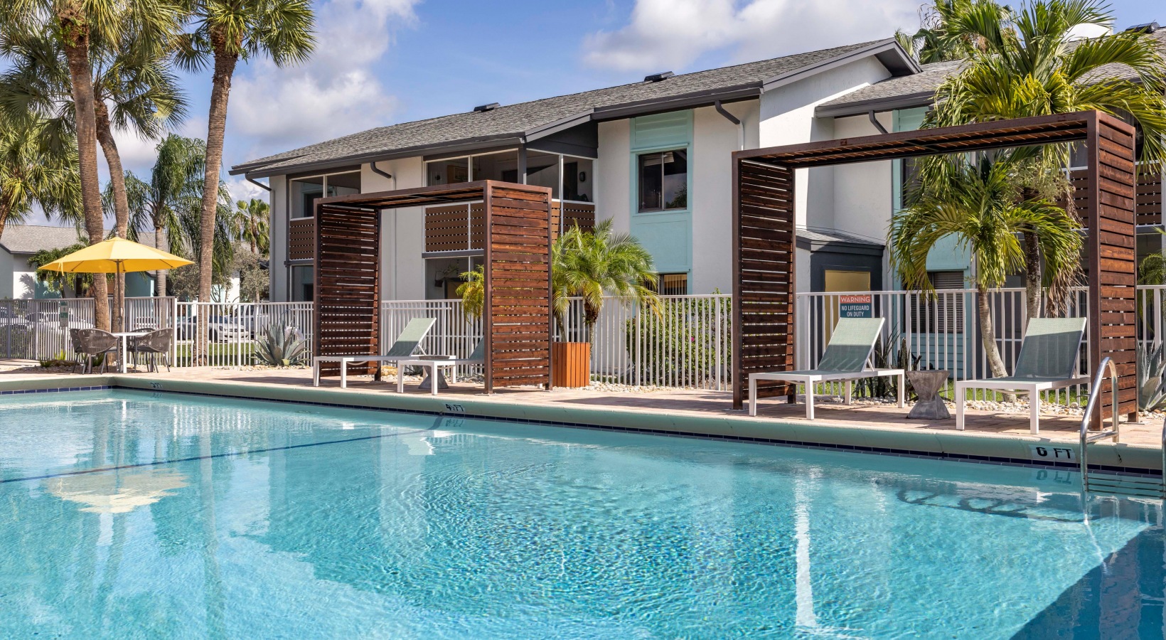 a pool with lounge chairs and umbrellas in front of a building at The Marino