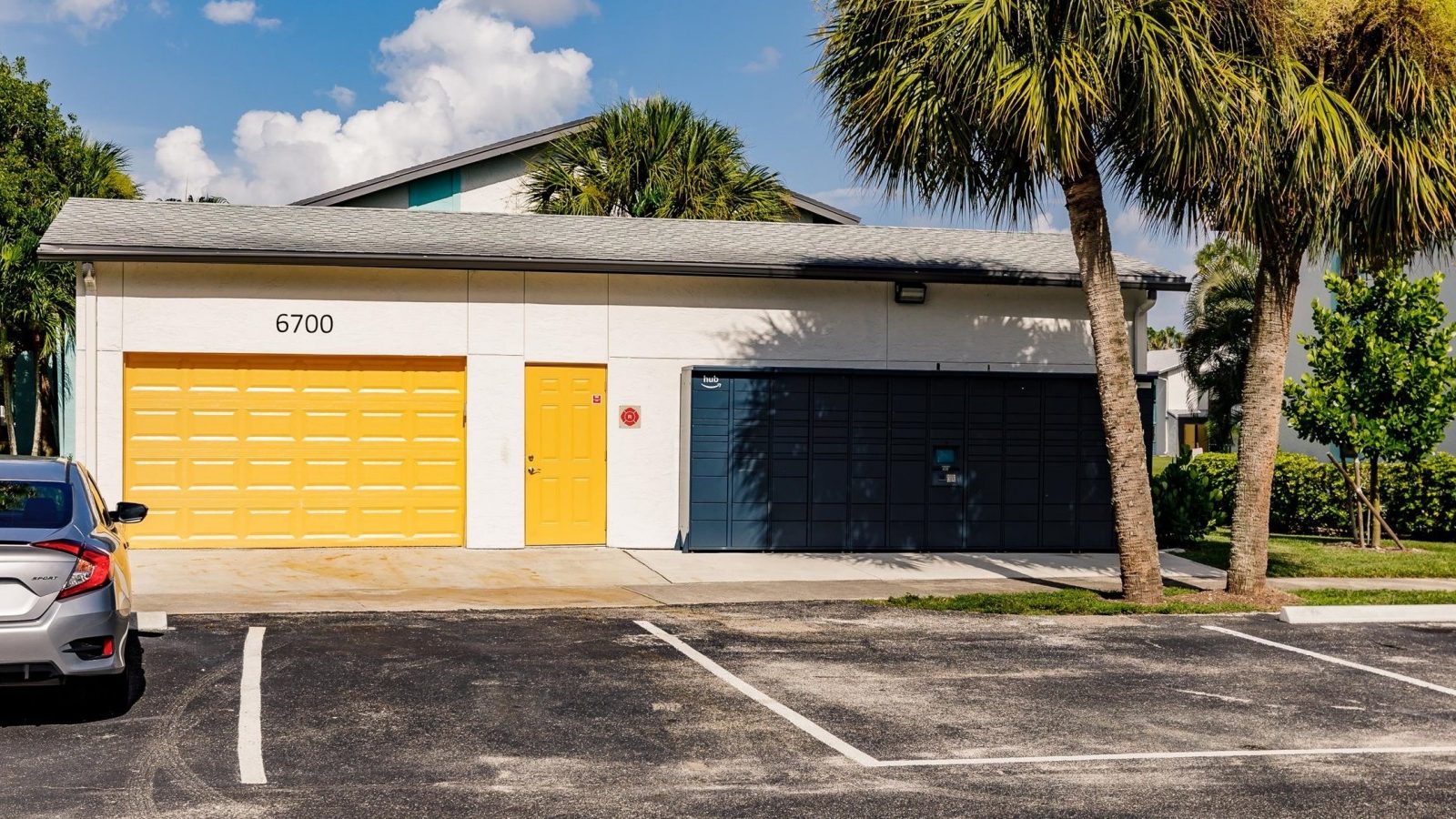a parking lot with two garages and a palm tree at The Marino