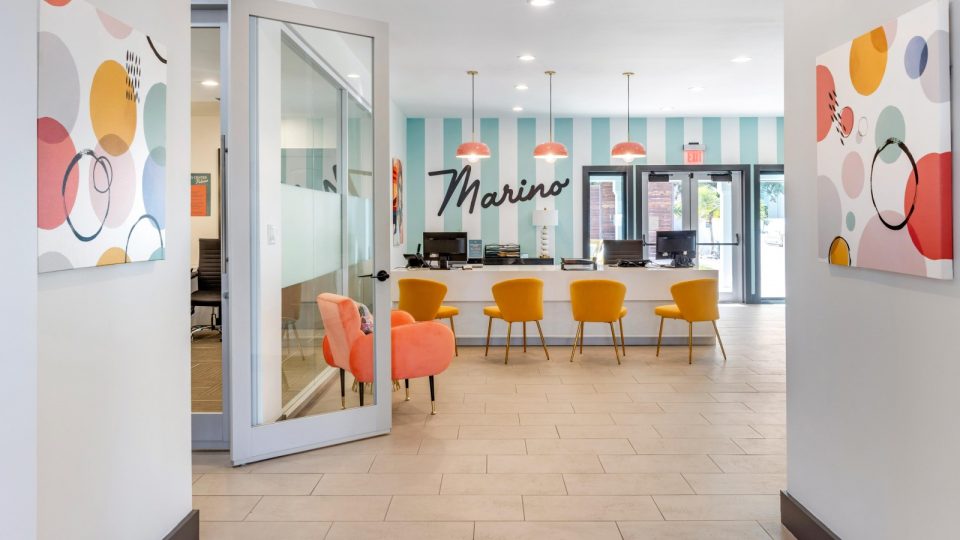 the lobby of a hotel with orange chairs and a large sign at The Marino
