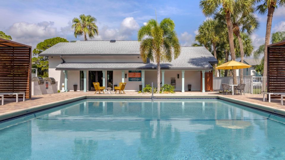 a pool with lounge chairs and palm trees in front of it at The Marino